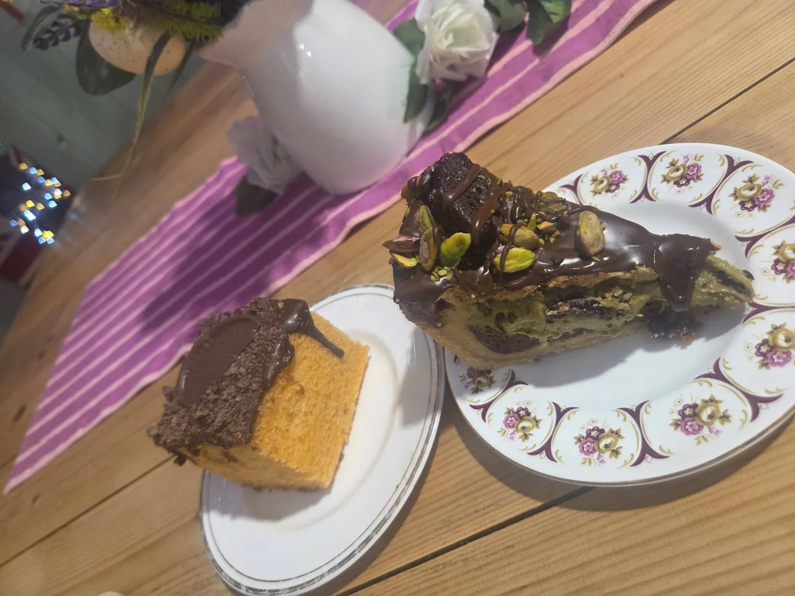 Slices of homemade chocolate pistachio cake and sponge on floral plates