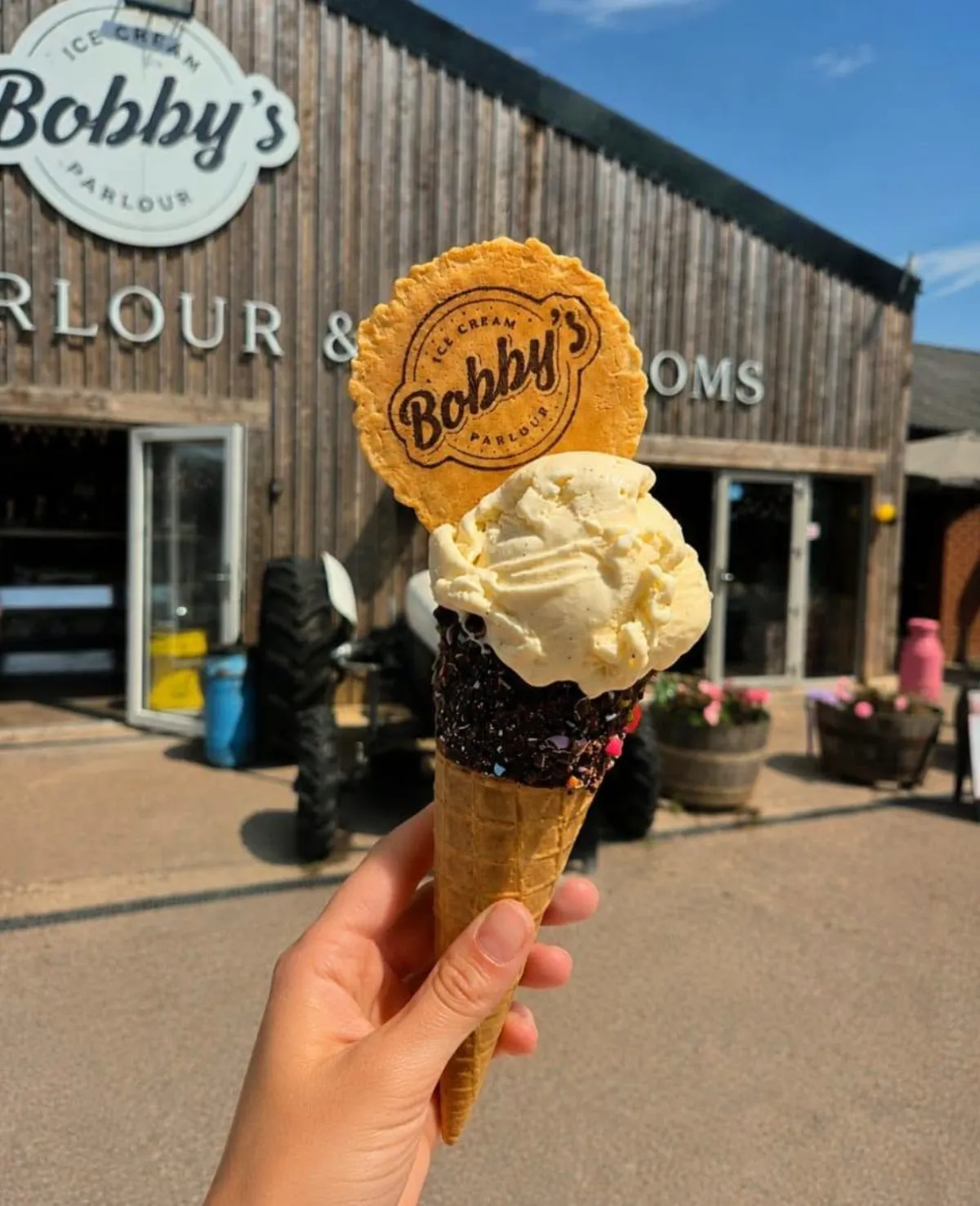 A Snugburys ice cream cone with a Bobby's wafer held up outside the timber parlour